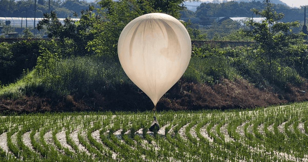 Foto de balão transportando objeto planando em cima de uma plantação